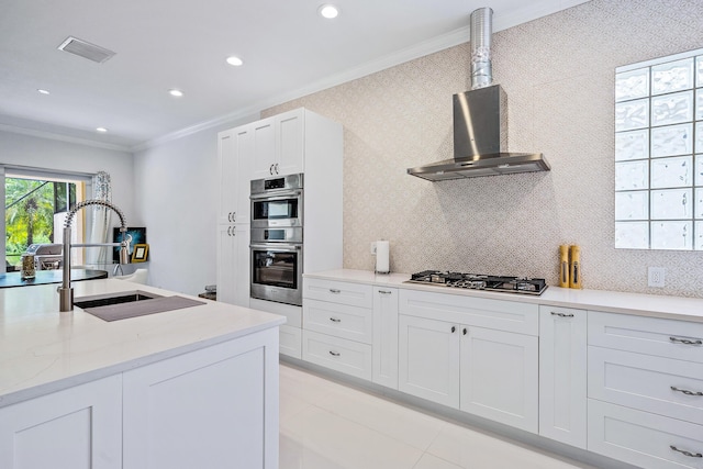 kitchen with ornamental molding, appliances with stainless steel finishes, a sink, wall chimney range hood, and recessed lighting