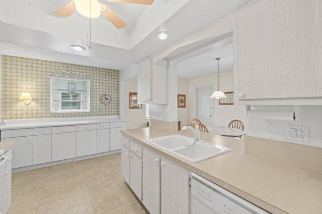 kitchen featuring a sink, light countertops, ceiling fan, dishwasher, and white cabinetry
