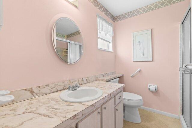bathroom featuring a shower stall, vanity, toilet, and baseboards