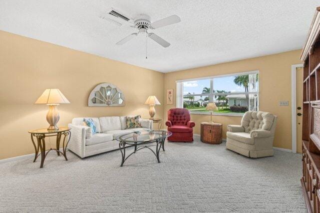 carpeted living room featuring a textured ceiling, a ceiling fan, and baseboards