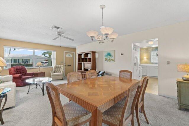 dining area featuring light colored carpet, a chandelier, and a ceiling fan