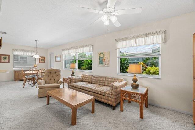 living area with light carpet and a ceiling fan