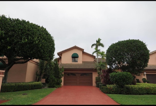 mediterranean / spanish home with stucco siding, driveway, a tile roof, and an attached garage