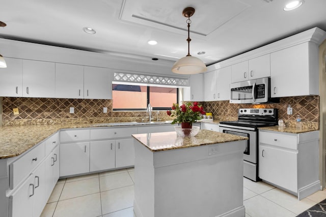 kitchen with stainless steel appliances, a sink, light tile patterned flooring, white cabinetry, and a kitchen island