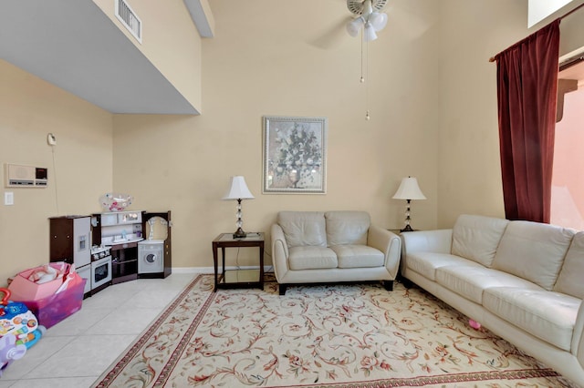 living area featuring light tile patterned floors, ceiling fan, and baseboards
