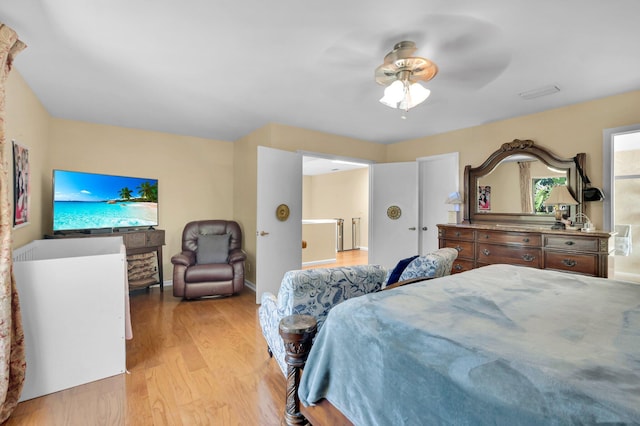bedroom with light wood-style floors, ensuite bathroom, and a ceiling fan