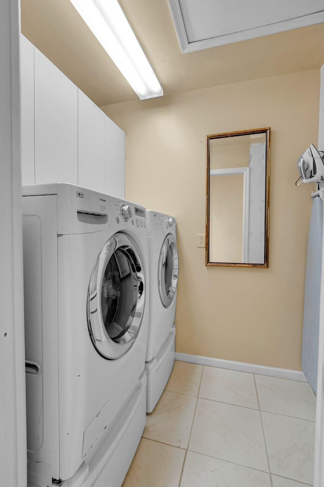 clothes washing area featuring cabinet space, washer and dryer, baseboards, and light marble finish flooring