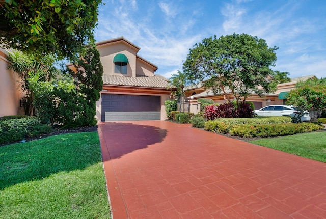 mediterranean / spanish home with stucco siding, a tile roof, a front yard, driveway, and an attached garage