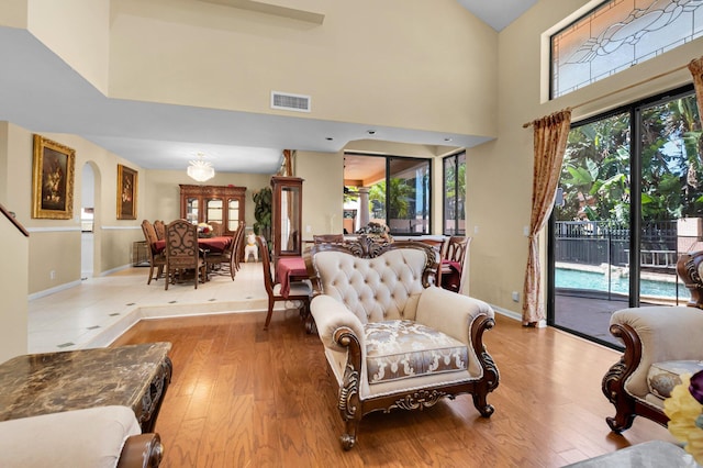 living room featuring wood finished floors, baseboards, and a high ceiling