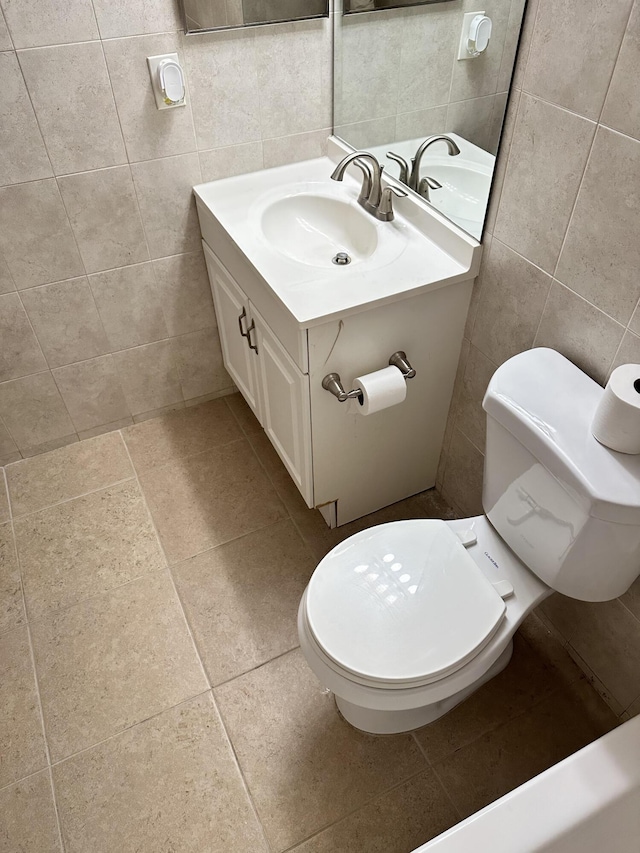 bathroom featuring tile walls, toilet, vanity, and tile patterned flooring