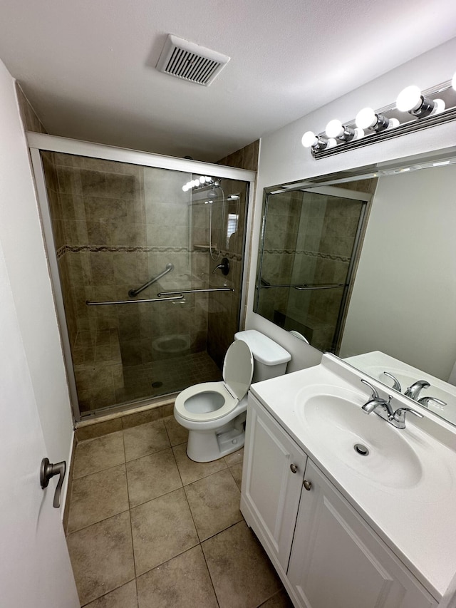 bathroom with a stall shower, tile patterned flooring, toilet, and vanity