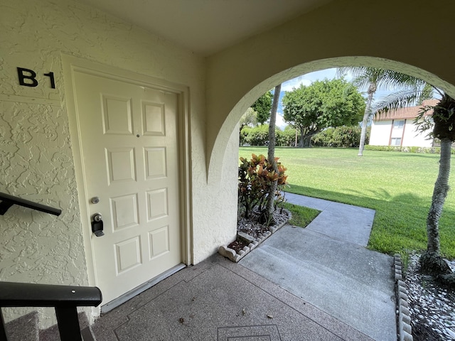 doorway to property with stucco siding and a lawn