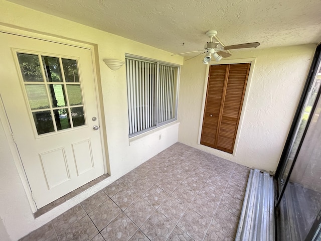 view of exterior entry with ceiling fan and stucco siding