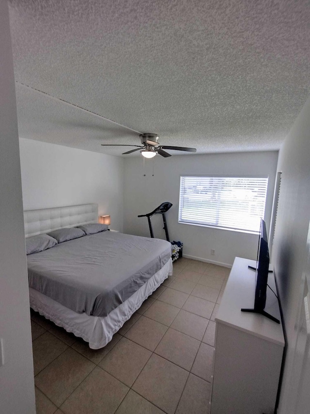 bedroom with a textured ceiling, light tile patterned flooring, and ceiling fan