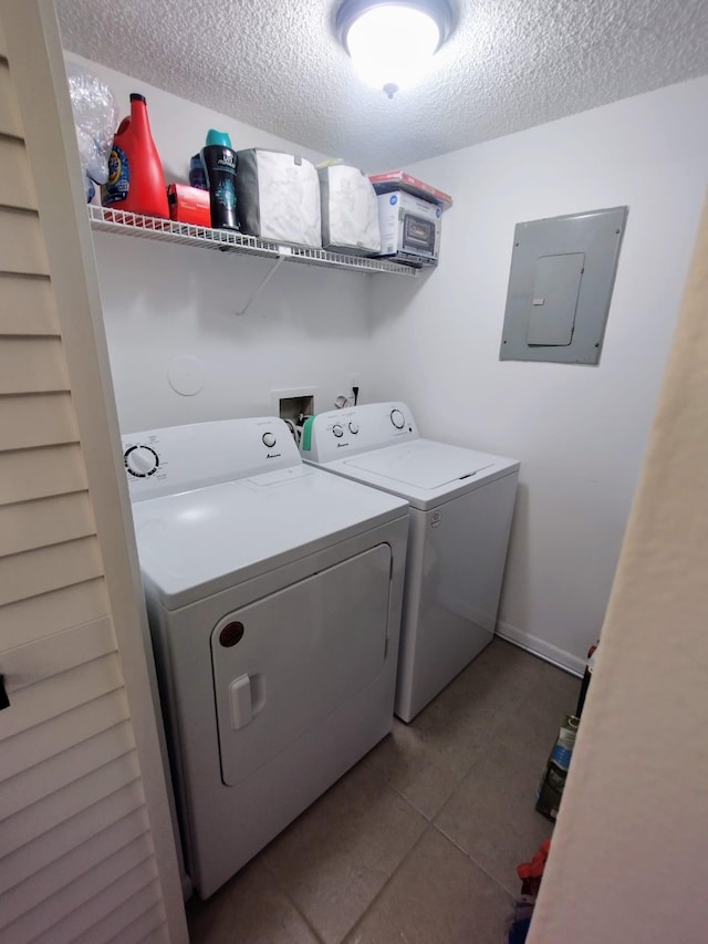 clothes washing area featuring washer and dryer, electric panel, a textured ceiling, tile patterned floors, and baseboards