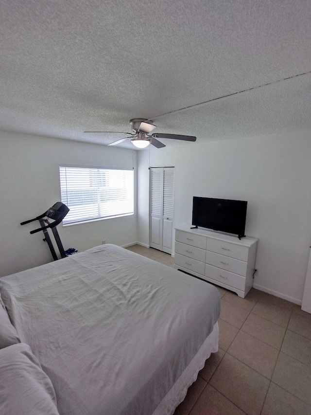 bedroom featuring a ceiling fan, light tile patterned floors, a textured ceiling, and baseboards