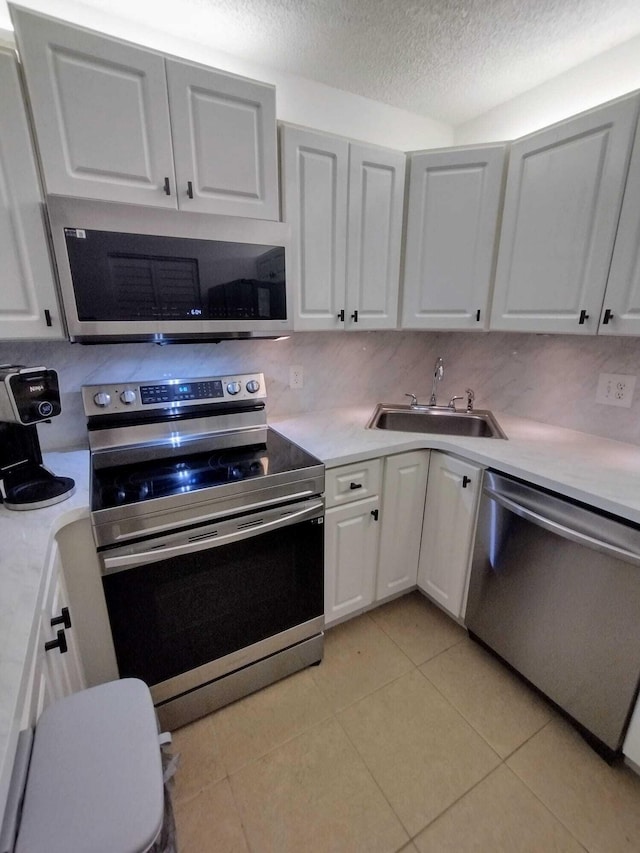 kitchen featuring stainless steel appliances, a sink, a textured ceiling, light countertops, and light tile patterned flooring