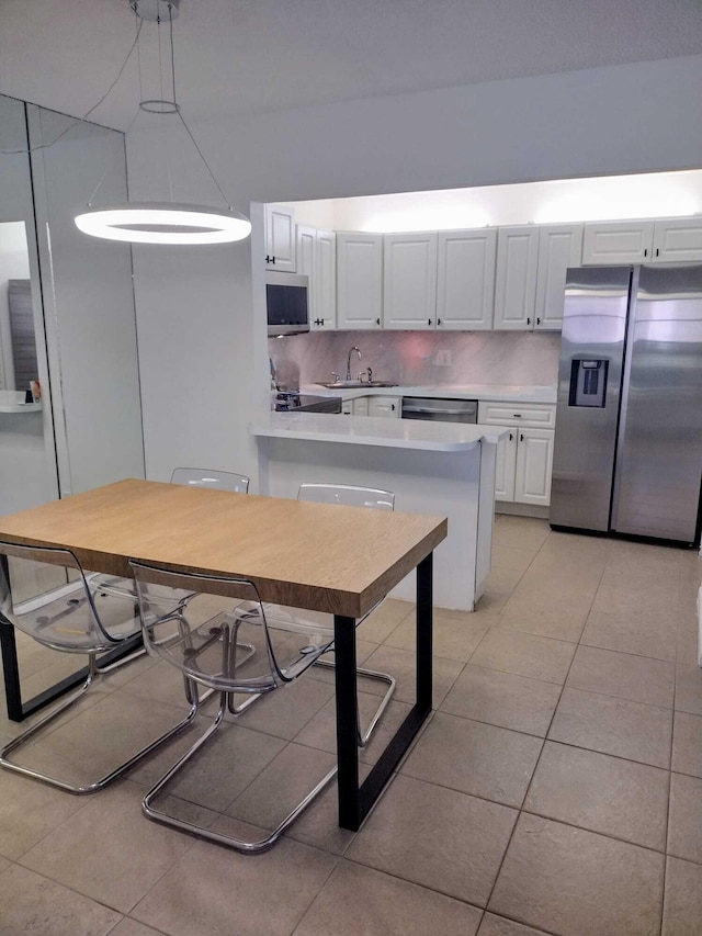 kitchen with stainless steel appliances, a sink, light tile patterned flooring, light countertops, and white cabinetry