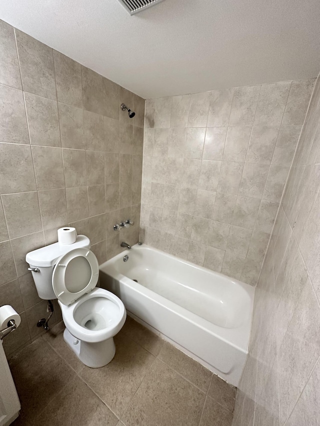 bathroom with tile walls, toilet, bathing tub / shower combination, and tile patterned flooring