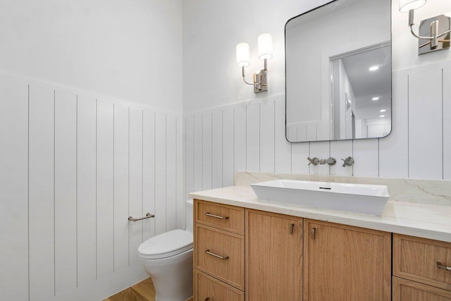 1105 NE 2nd Ave, Delray Beach, FL 33444 - bathroom with toilet, vanity, wainscoting, a decorative wall, and wood finished floors
