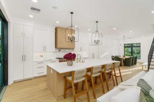 1105 NE 2nd Ave, Delray Beach, FL 33444 - kitchen featuring light wood finished floors, paneled built in fridge, a center island with sink, light countertops, and a chandelier