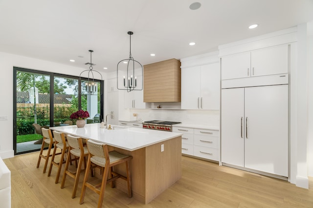 1105 NE 2nd Ave, Delray Beach, FL 33444 - kitchen with stainless steel gas cooktop, a chandelier, a kitchen island with sink, built in refrigerator, and light countertops