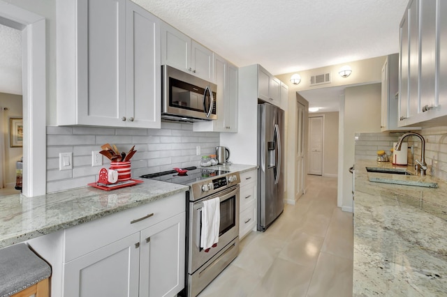 6328 Longboat Ln Unit 302, Boca Raton, FL 33433 - kitchen featuring appliances with stainless steel finishes, backsplash, a sink, light stone countertops, and white cabinets