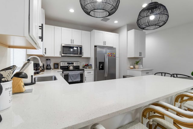 18 S D St, Lake Worth Beach, FL 33460 - kitchen featuring stainless steel appliances, a sink, a breakfast bar area, white cabinets, and a peninsula