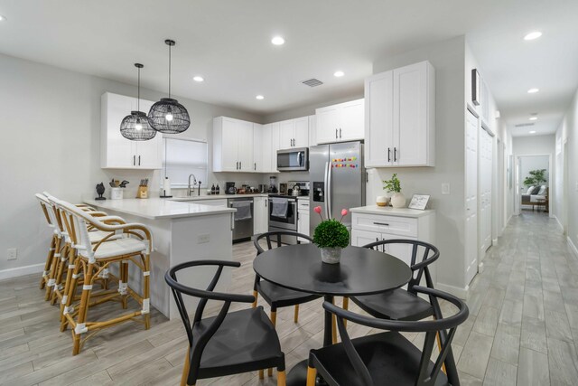 18 S D St, Lake Worth Beach, FL 33460 - kitchen featuring stainless steel appliances, a peninsula, baseboards, white cabinets, and light wood-style flooring