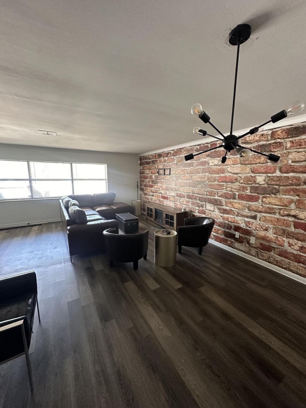 living area with wood finished floors, brick wall, and baseboards
