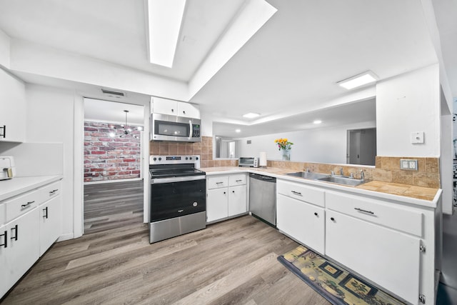 356 SE Prima Vista Blvd, Port Saint Lucie, FL 34983 - kitchen featuring stainless steel appliances, light wood finished floors, light countertops, a sink, and white cabinetry
