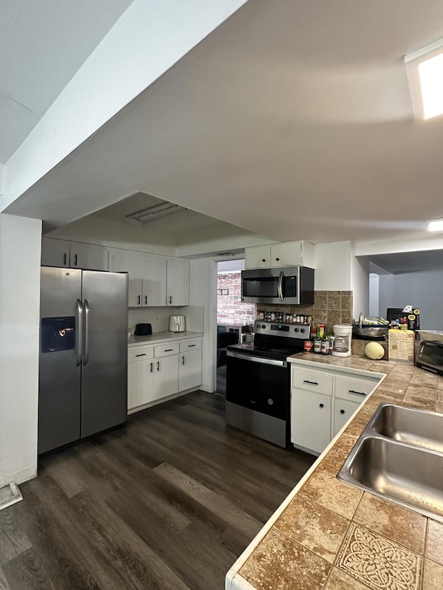 kitchen featuring stainless steel appliances, white cabinets, dark wood-style flooring, and a sink
