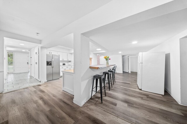 356 SE Prima Vista Blvd, Port Saint Lucie, FL 34983 - kitchen featuring stainless steel fridge with ice dispenser, freestanding refrigerator, white cabinets, a breakfast bar, and light wood-type flooring