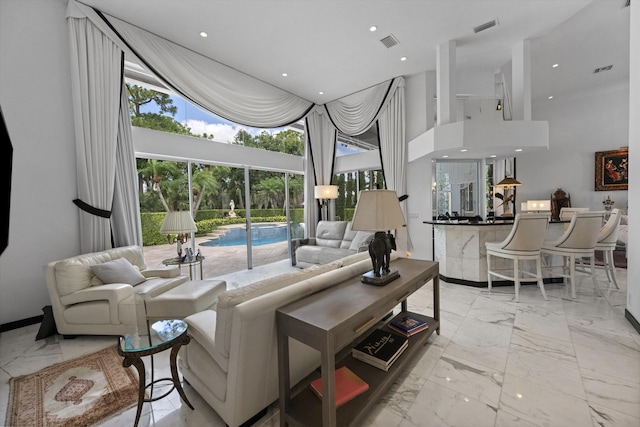 living area with marble look tile flooring, a high ceiling, and recessed lighting