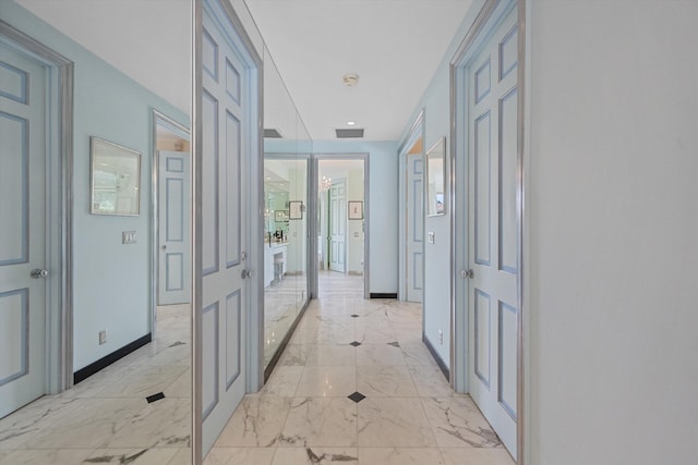 hallway featuring light marble finish floors, baseboards, and french doors