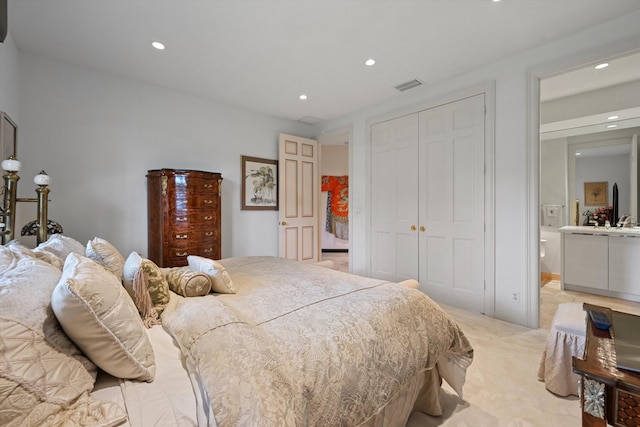 bedroom with light carpet, a closet, recessed lighting, and ensuite bathroom