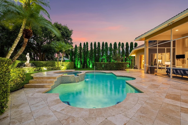 pool at dusk with a patio and a pool with connected hot tub