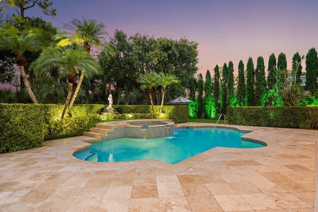 pool at dusk featuring a patio area and a pool with connected hot tub