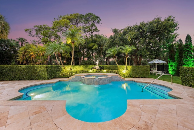 view of pool with a patio, fence, a pool with connected hot tub, and view of scattered trees
