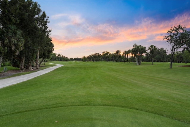 view of home's community featuring golf course view, a yard, and view of scattered trees