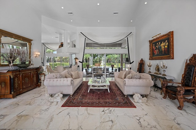 living room with recessed lighting, marble finish floors, and a towering ceiling