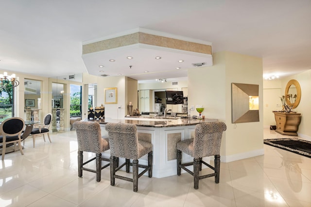 kitchen featuring a kitchen breakfast bar, dark stone counters, healthy amount of natural light, light tile patterned flooring, and recessed lighting
