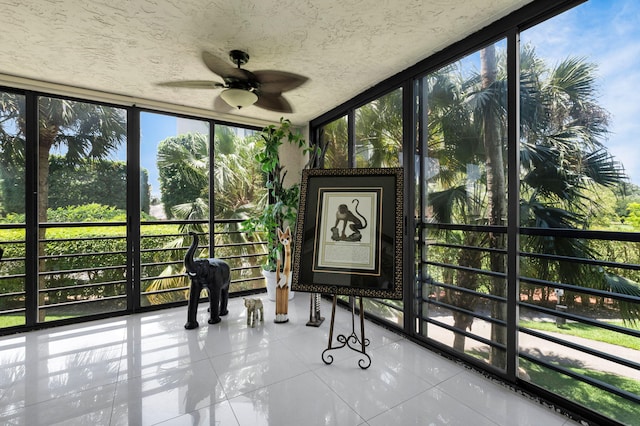 sunroom with a wall of windows, ceiling fan, tile patterned floors, and a textured ceiling