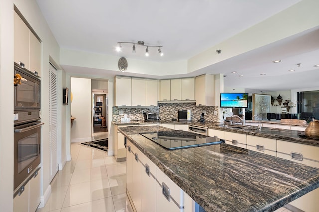 kitchen featuring black appliances, a kitchen island, backsplash, light tile patterned floors, and a sink
