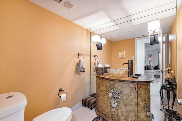 bathroom with toilet, vanity, and baseboards