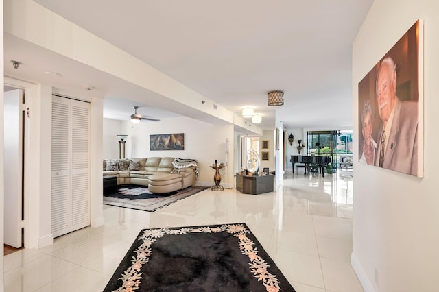 tiled living room featuring baseboards and ceiling fan
