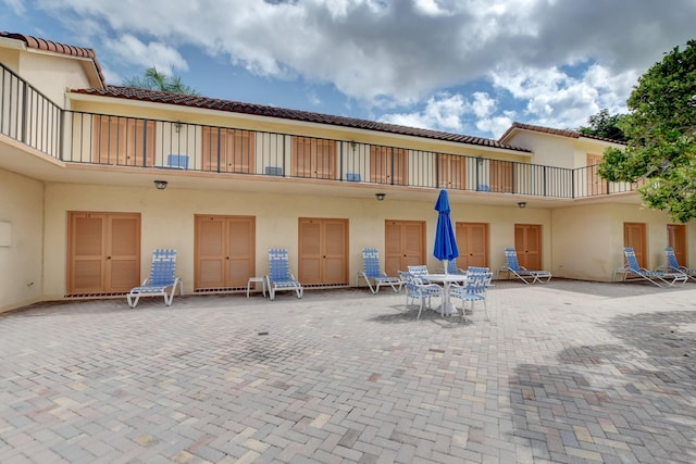 rear view of property with stucco siding, a patio, a tiled roof, and outdoor dining area