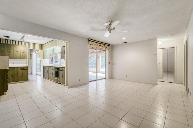 spare room with ceiling fan, a textured ceiling, and light tile patterned floors