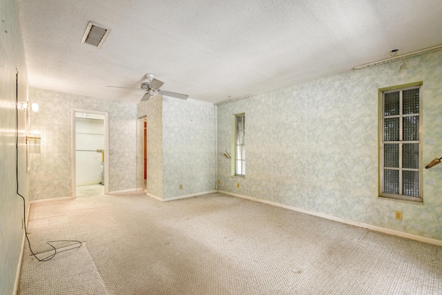 carpeted empty room with a textured ceiling, a ceiling fan, and baseboards