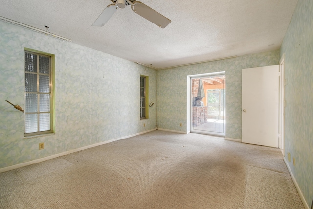 carpeted spare room featuring ceiling fan, a textured ceiling, and wallpapered walls